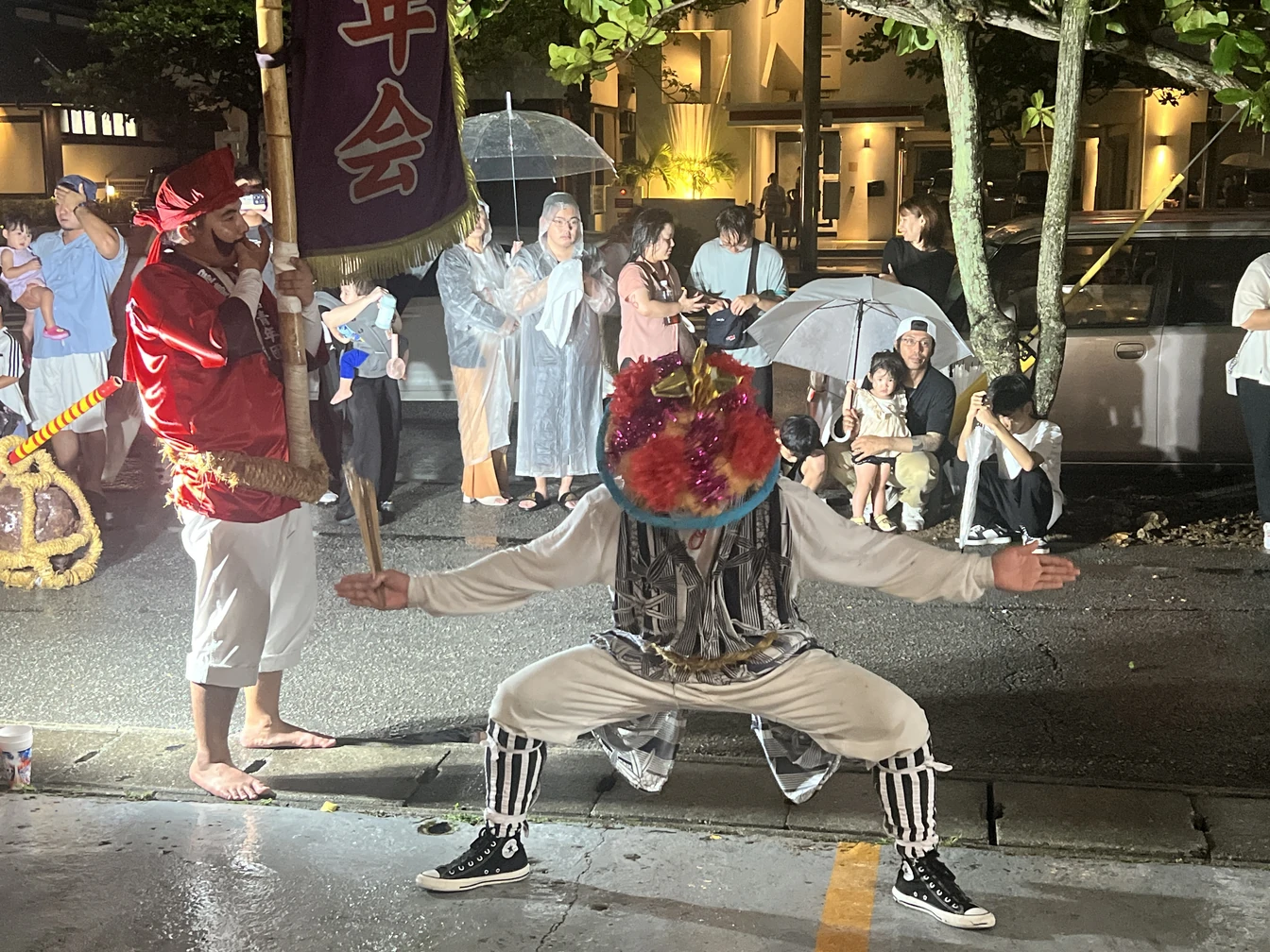 大きく腕を広げて演舞する屋慶名青年会の方と、周囲で見守る来場者