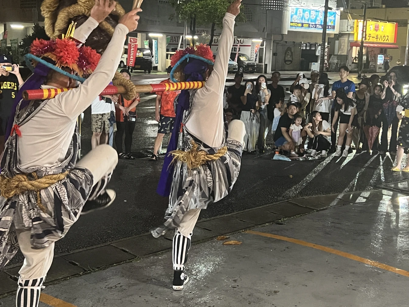 屋外でのエイサー演舞を、大人や子どもたちが集まって見守る様子