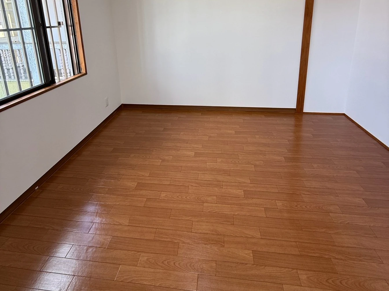 施工後の居室。窓の横の壁を白く整え、床を木目柄に仕上げた様子